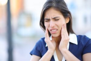 Woman clutching at jaw in pain. 